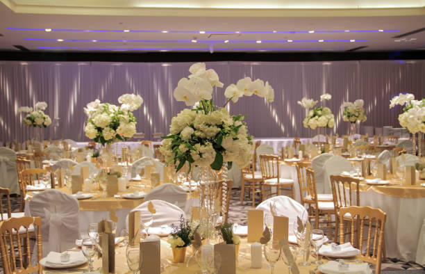 Indoor gold-themed ballroom with white orchid arrangements and lavender uplighting